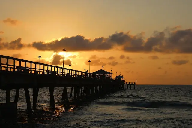 A view of the morning sun rising over a wooden bridge over the sea